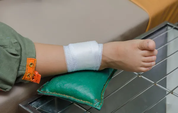 Niño con vendaje en la pierna y acostado en la cama del hospital —  Fotos de Stock