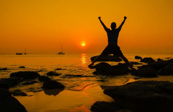 Salto feliz durante o pôr do sol na praia — Fotografia de Stock