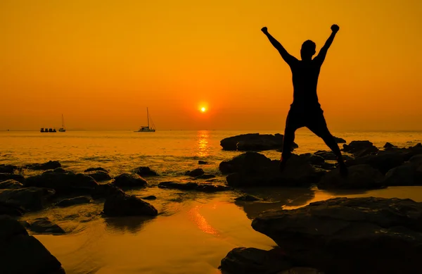 Salto feliz durante o pôr do sol na praia — Fotografia de Stock