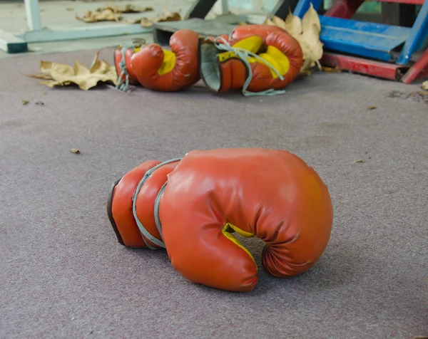Viejos guantes de boxeo rojos abandonados debajo del escenario — Foto de Stock