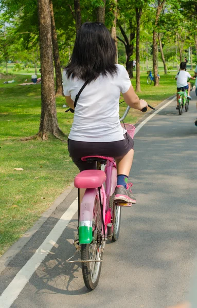 Jovencita con bicicleta en un camino en el parque . —  Fotos de Stock