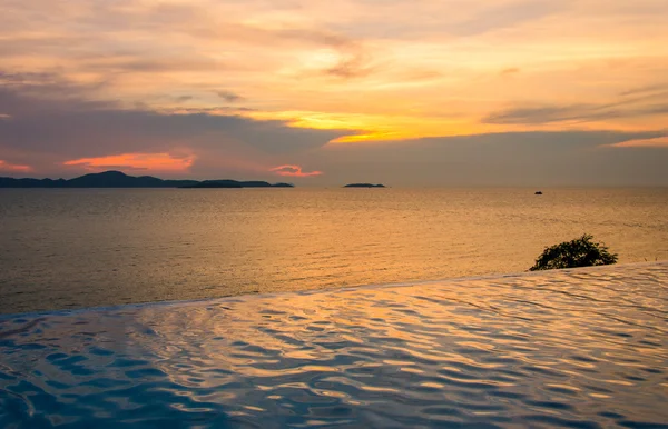 Luxusní plavecký bazén přímo u moře při západu slunce — Stock fotografie