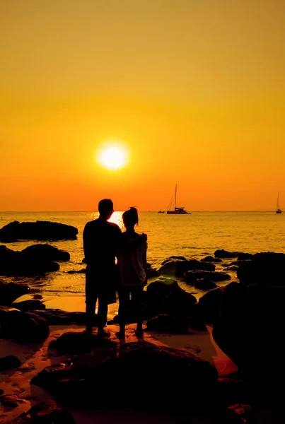 Liebespaar steht auf einem Felsen am Meer und beobachtet die Sonne — Stockfoto