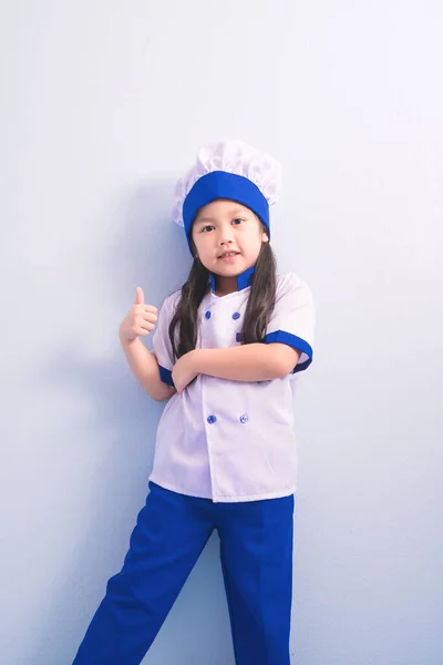 服やシェフキャップで驚くほどの笑顔で幸せな女の子 料理人を目指す子供の夢は — ストック写真