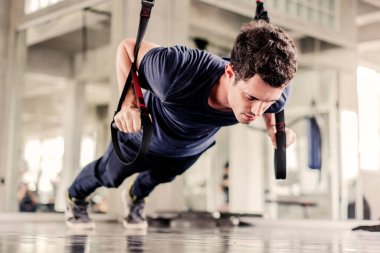 Sporcu ya da yakışıklı spor salonundaki karın kaslarını güçlendirmek için spor kemerleriyle egzersiz yapıyor..