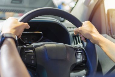 Direksiyonda telefon ve kontrol düğmeleri olan direksiyonda insan eli var..