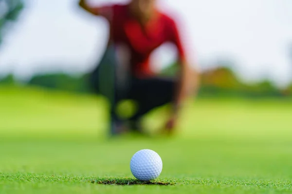 ゴルフ場で緑の上に穴にゴルフボールを入れてゴルファー — ストック写真