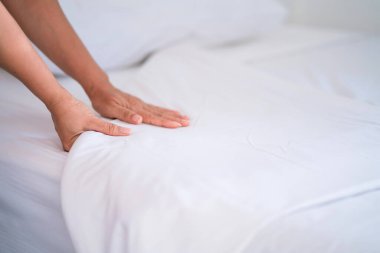 Kadın El yatak odasına beyaz çarşaf serdi ya da hizmetçi elleri otel odasında yatak hazırladı..