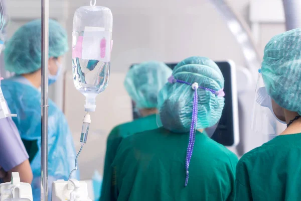 Drip system and saline bag with Surgeon operates in the operating room at Hospital.