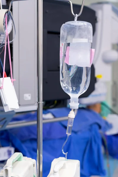 Drip system and saline bag with Surgeon operates in the operating room at Hospital.