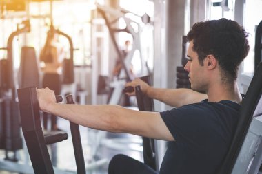 Yakışıklı adam spor aletini indiriyor ve spor salonunda spor yapıyor..