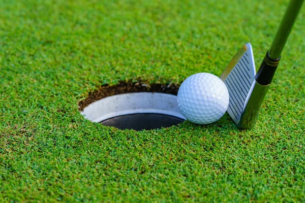 Golf ball and golf club in beautiful golf course at Thailand. golf equipment resting on green grass background.