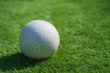 Yapay arka planda yeşil çimlerde plastik futbol topu.