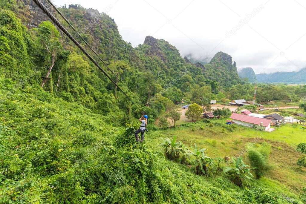 man going on zipline adventure through the forest in Lao.