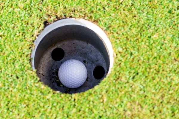 ゴルフ場のカップの穴の中のゴルフボール — ストック写真