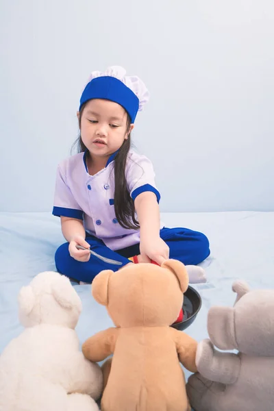 Happy girls in clothes and chef cap playing with a doll to be a chef. child dreams of becoming a chef.