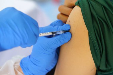 Hemşire elinde enjeksiyon için bir şırınga tutarak hastaya hastanede aşı veriyor. Sağlık Hizmetleri Konsepti.