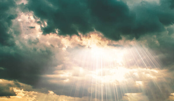 Sun beams shining through dark clouds on sky nature background