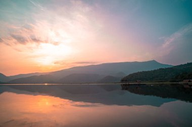 Panorama scenic of mountain lake with perfect reflection at sunrise. beautiful mountain range landscape with pink pastel sky with hills on background and reflected in water. Nature lake landscape