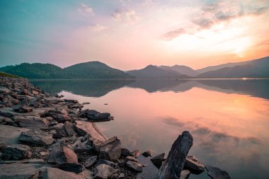Panorama scenic of mountain lake with perfect reflection at sunrise. beautiful mountain range landscape with pink pastel sky with hills on background and reflected in water. Nature lake landscape