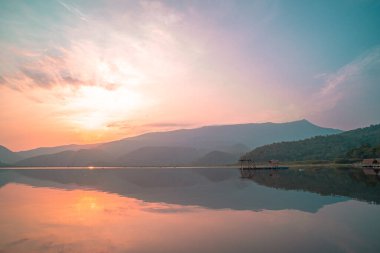 Panorama scenic of mountain lake with perfect reflection at sunrise. beautiful mountain range landscape with pink pastel sky with hills on background and reflected in water. Nature lake landscape