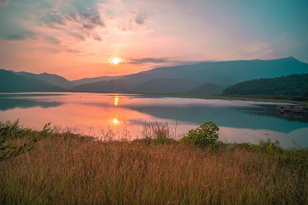 Panorama scenic of mountain lake with perfect reflection at sunrise. beautiful mountain range landscape with pink pastel sky with hills on background and reflected in water. Nature lake landscape