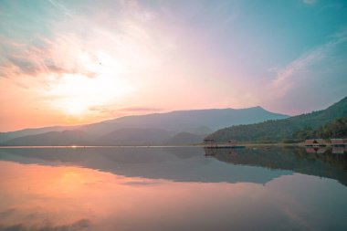 Panorama scenic of mountain lake with perfect reflection at sunrise. beautiful mountain range landscape with pink pastel sky with hills on background and reflected in water. Nature lake landscape