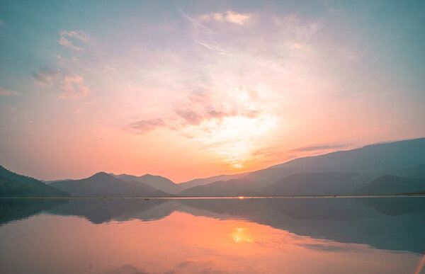 Живописный пейзаж горного озера с прекрасным видом на восход солнца. красивый горный хребет пейзаж с розовым пастельным небом с холмами на заднем плане и отражается в воде. Озерный пейзаж