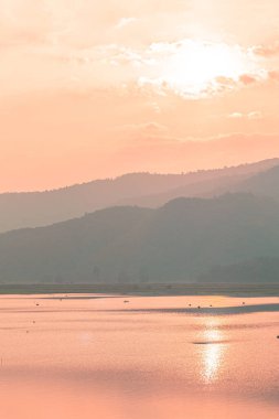 Panorama scenic of mountain lake with perfect reflection at sunrise. beautiful mountain range landscape with pink pastel sky with hills on background and reflected in water. Nature lake landscape
