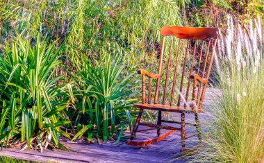 Empty rocking chair in garden at summer sunset