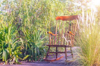 Empty rocking chair in garden at summer sunset