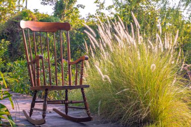 Empty rocking chair in garden at summer sunset
