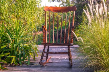 Empty rocking chair in garden at summer sunset