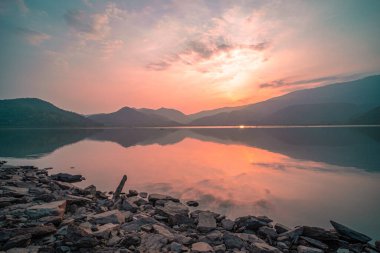 Panorama scenic of mountain lake with perfect reflection at sunrise. beautiful mountain range landscape with pink pastel sky with hills on background and reflected in water. Nature lake landscape