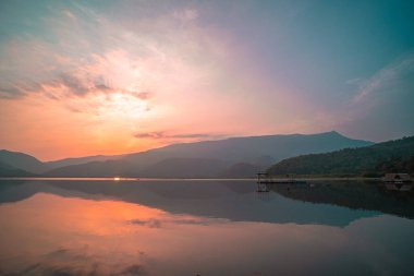 Panorama scenic of mountain lake with perfect reflection at sunrise. beautiful mountain range landscape with pink pastel sky with hills on background and reflected in water. Nature lake landscape