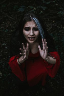 Kozalaklı bir ormanda, tarihi bir elbise giymiş bir kız.