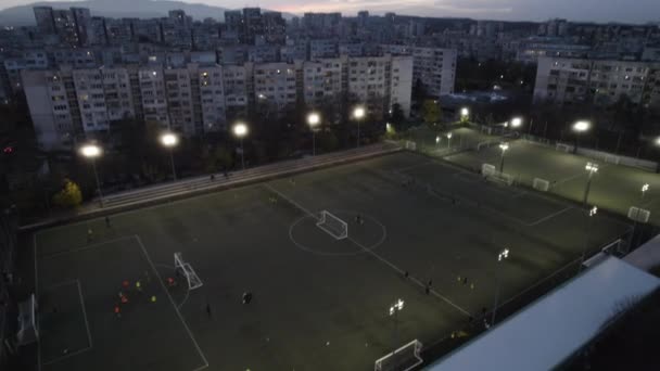Joueurs de football amateur jouant le jeu dans le terrain du parc de la ville le soir — Video