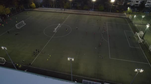 市内でゲームをプレイアマチュアサッカー選手と夜のサッカーピッチの空中ビュー — ストック動画