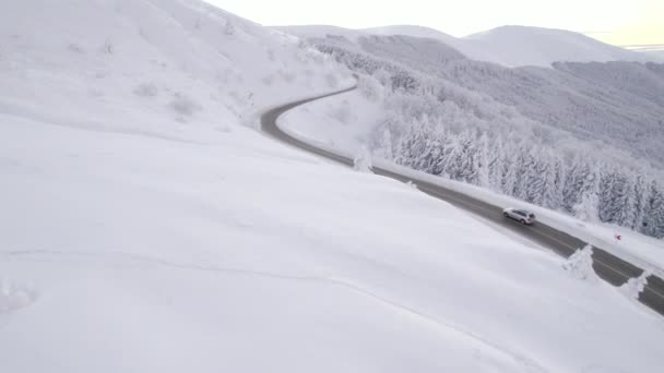 İnsansız hava aracı kış koşullarında dik dağ yolunda gümüşi SUV hızını takip ediyor. — Stok video