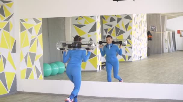 美しいですスポーティなブルネット女性で青スポーツウェア持ち上げアクアバッグ — ストック動画