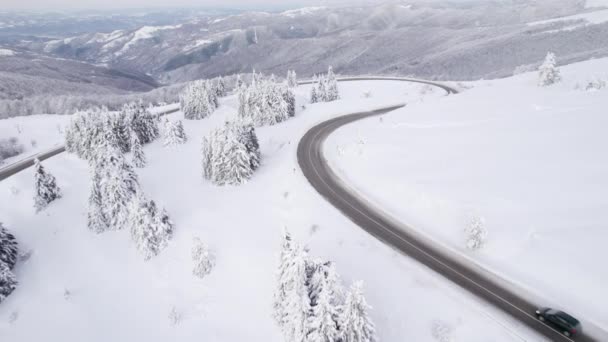 Drone sigue la conducción de SUV negro en condiciones de invierno en el sinuoso camino de montaña — Vídeos de Stock