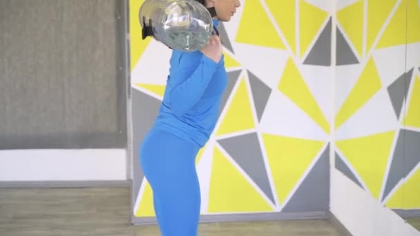 Вид сбоку на женщин, занимающихся фитнесом на приседаниях перед большим зеркалом в тренажерном зале — стоковое видео