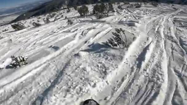 Człowiek snowboarding na stoku narciarskim w górskim kurorcie w słoneczny dzień — Wideo stockowe