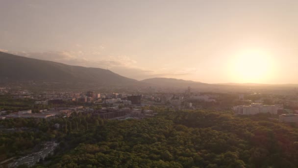 Vista aérea de edificios habitables y parque urbano en Sofía con horizonte al atardecer — Vídeos de Stock