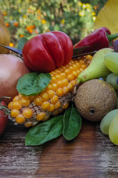 Mısır, kırmızı domates, armut, soğan, kırmızı dolma biber ve bulanık arkaplanda yeşil fesleğen yaprakları.