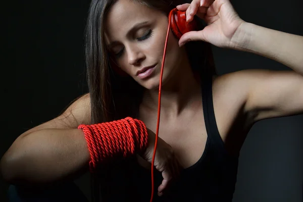 Una hermosa joven con los auriculares rojos —  Fotos de Stock