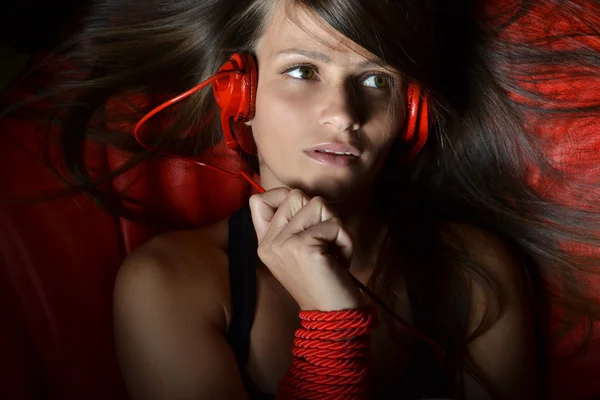 Een mooie jonge vrouw met de rode hoofdtelefoon — Stockfoto