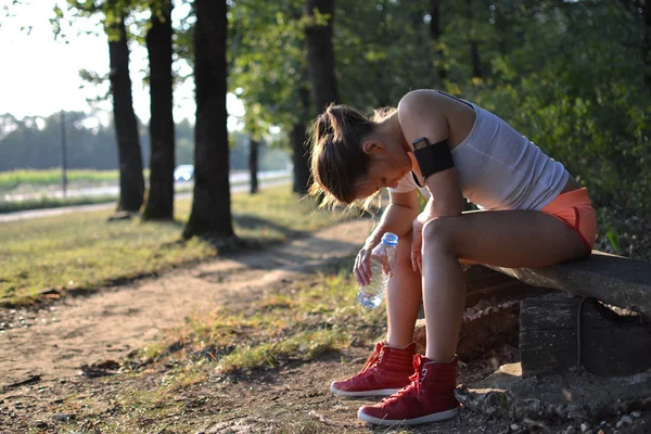 Egzersiz yaptıktan sonra parkta oturan genç bir kadın — Stok fotoğraf
