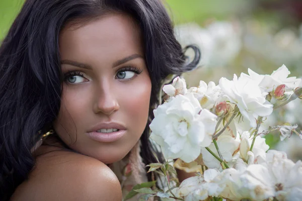 Brunette posing near white roses — Stock Photo, Image