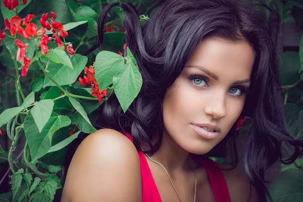 Brunette standing near the bush with red flowers — Stock Photo, Image